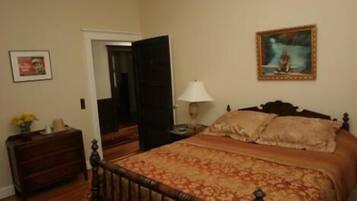 A bedroom with a wooden bed, a nightstand, a lamp, and a painting on the wall.