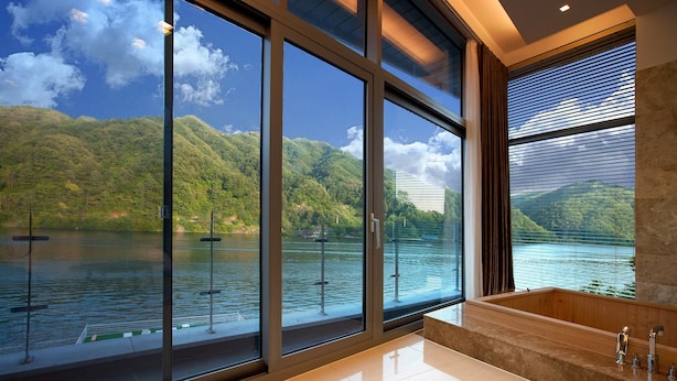 A modern bathroom with large windows, a bathtub, and a view of a lake and mountains. - Ethren Resort (Gapyeong)