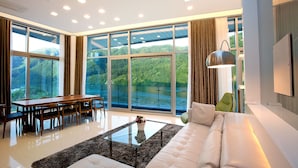 A modern living room with a large glass window, a sofa, a coffee table, and a dining area. - Ethren Resort (Gapyeong)
