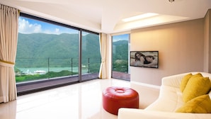 A modern living room with a large sliding glass door leading to a balcony with a mountain view. - Ethren Resort (Gapyeong)