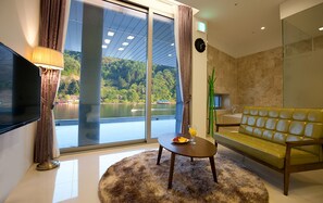 A modern living room with a large window, a sofa, a coffee table, and a TV.