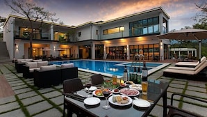 A modern house with a swimming pool, outdoor seating, and a dining area with food and drinks. - Ethren Resort (Gapyeong)