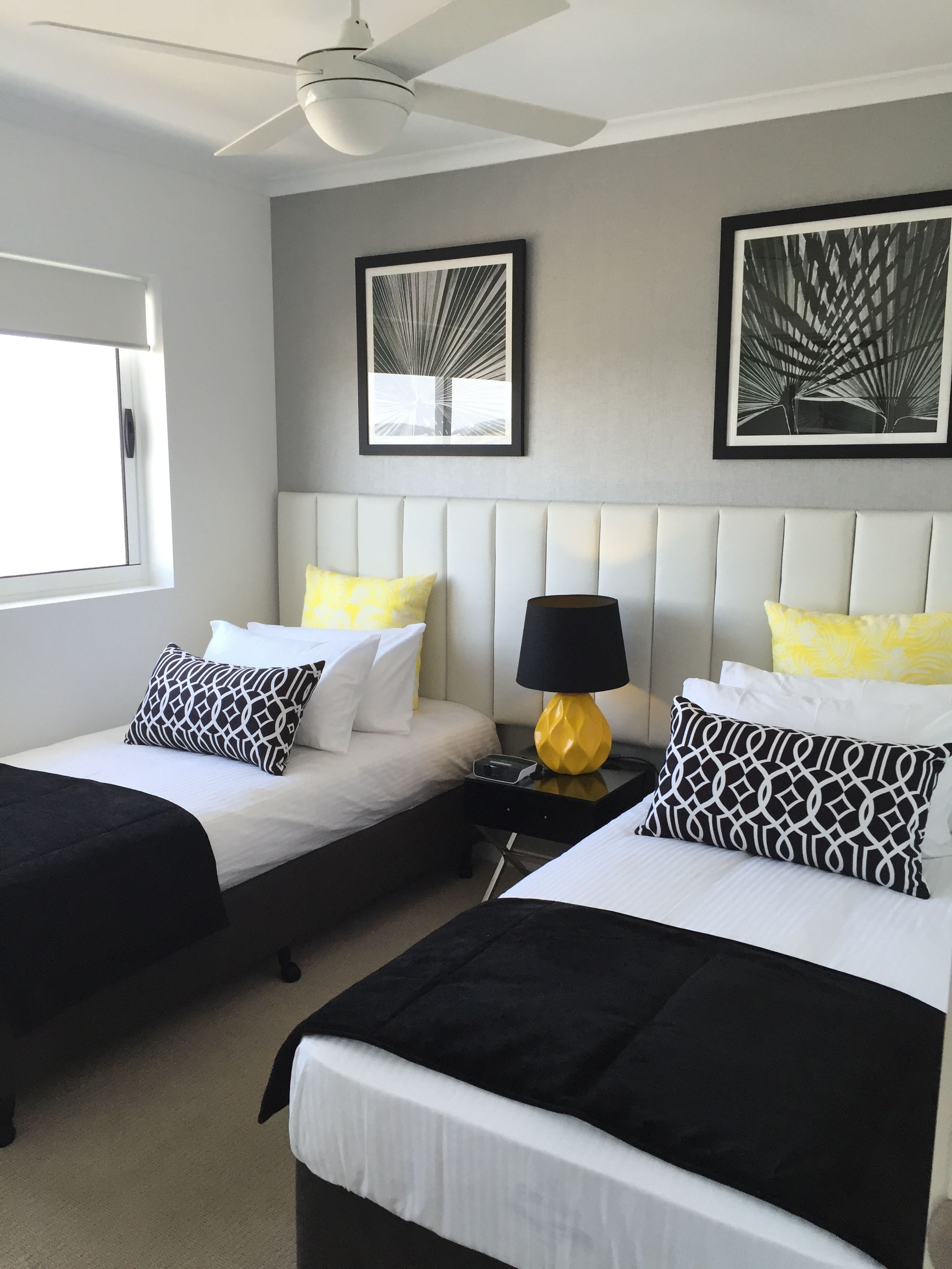 A hotel room with two beds, a ceiling fan, and artwork on the walls.