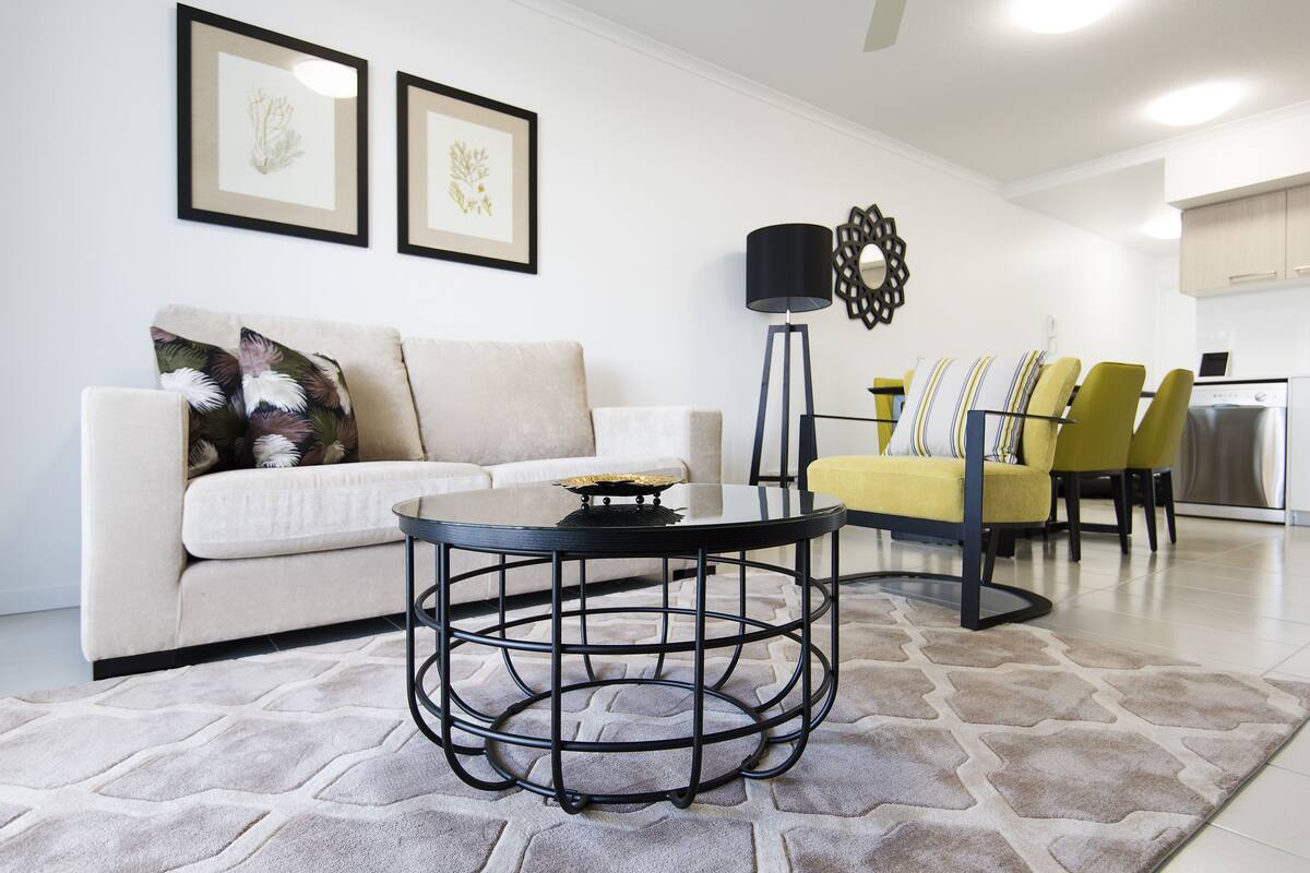 A modern living room with a round coffee table, a sofa, and a yellow dining area.