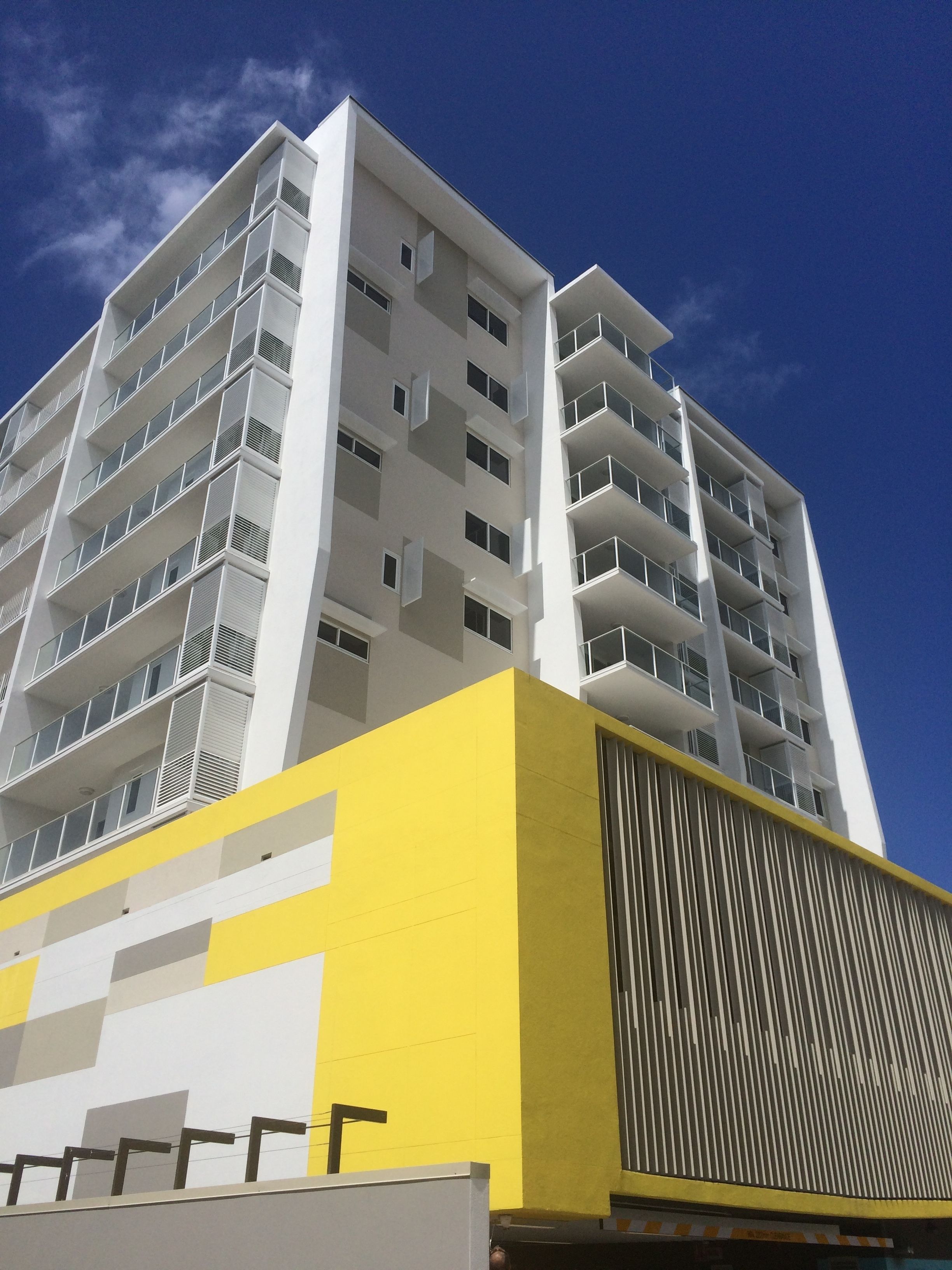 A high-rise building with multiple balconies and a yellow facade.