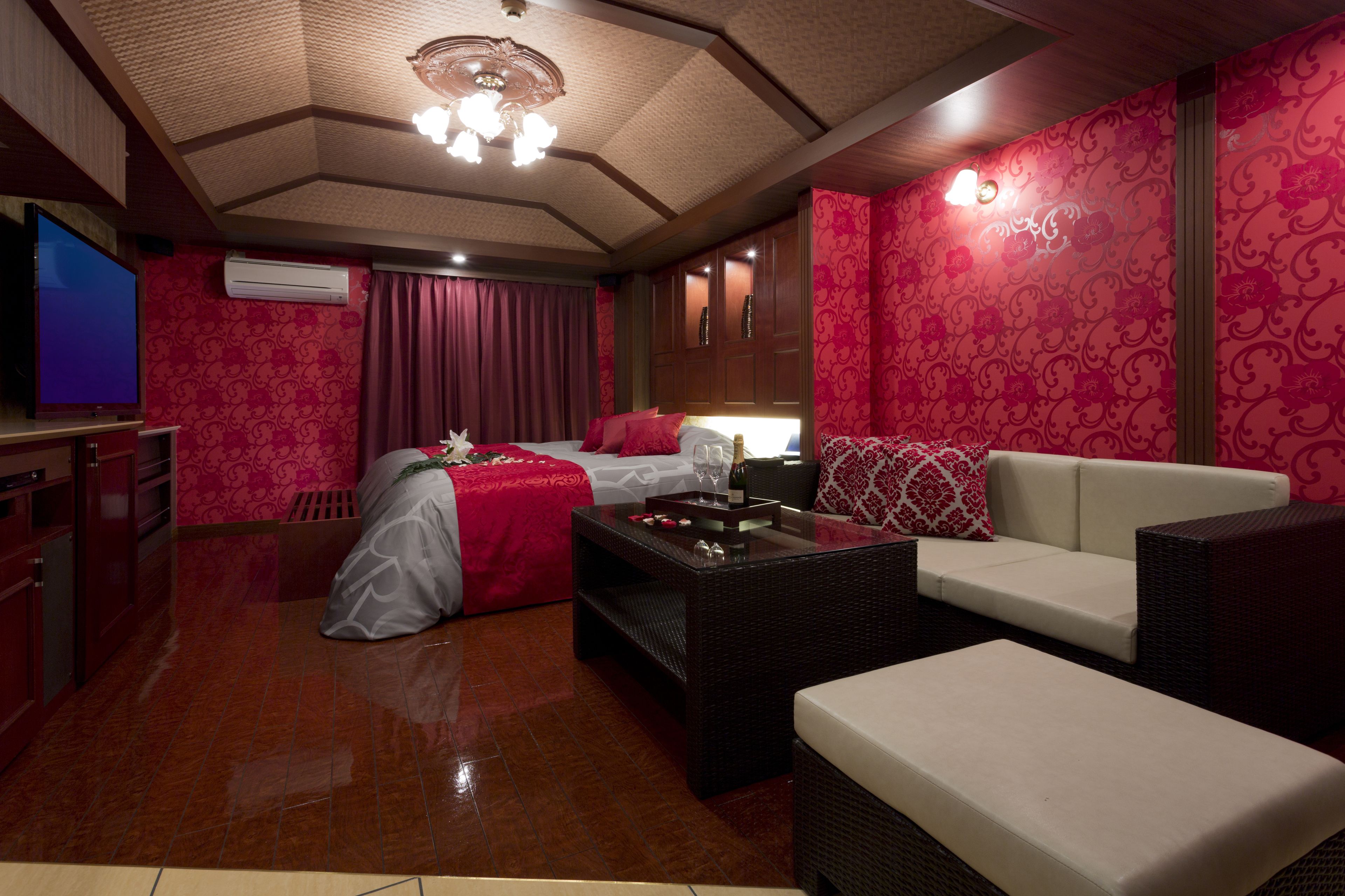 A hotel room with a large bed, a sofa, a coffee table, and a television.