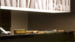 A reception desk with a 'FRONT' sign, a telephone, and a wooden object on the counter. - Hotel Watergate Okayama - Adults Only (Okayama)