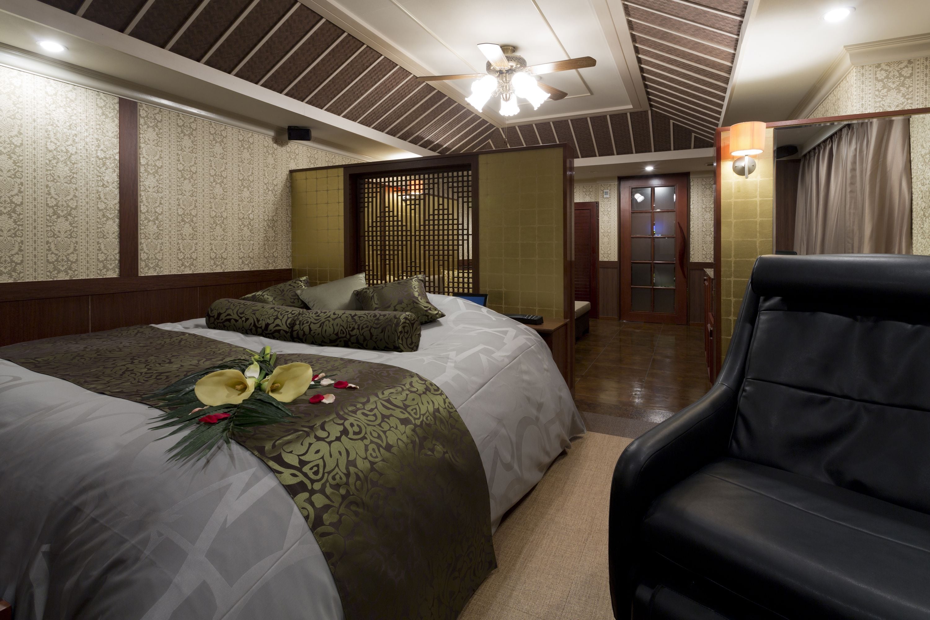 A hotel room with two beds, a ceiling fan, and a black leather chair.