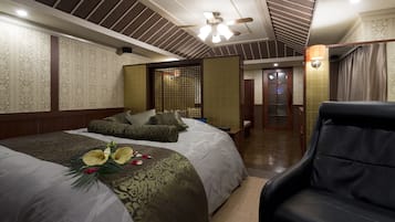 A hotel room with two beds, a ceiling fan, and a black leather chair.