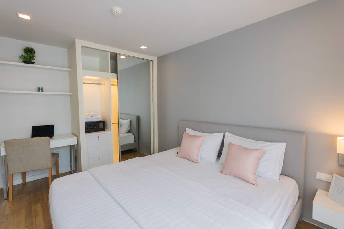 Una habitación de hotel moderna con una cama grande, un escritorio y un armario.