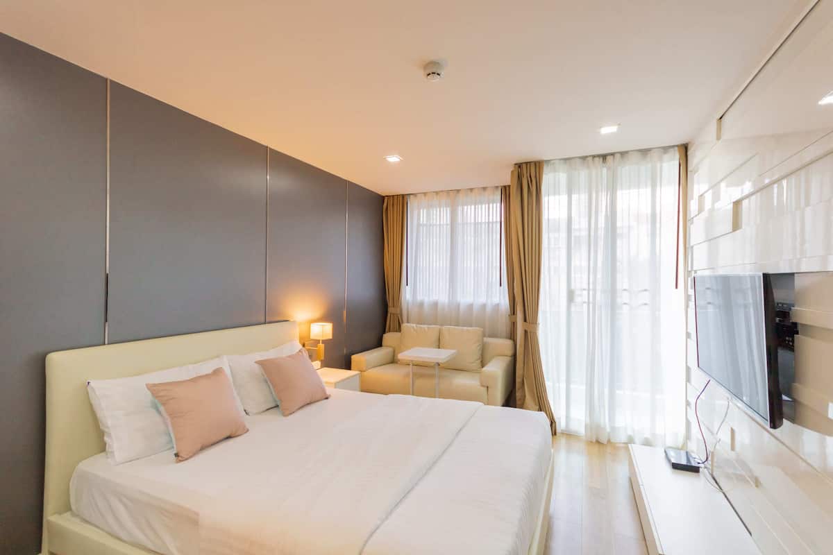 Una habitación de hotel moderna con una cama grande, un sofá, un televisor y una mesita.