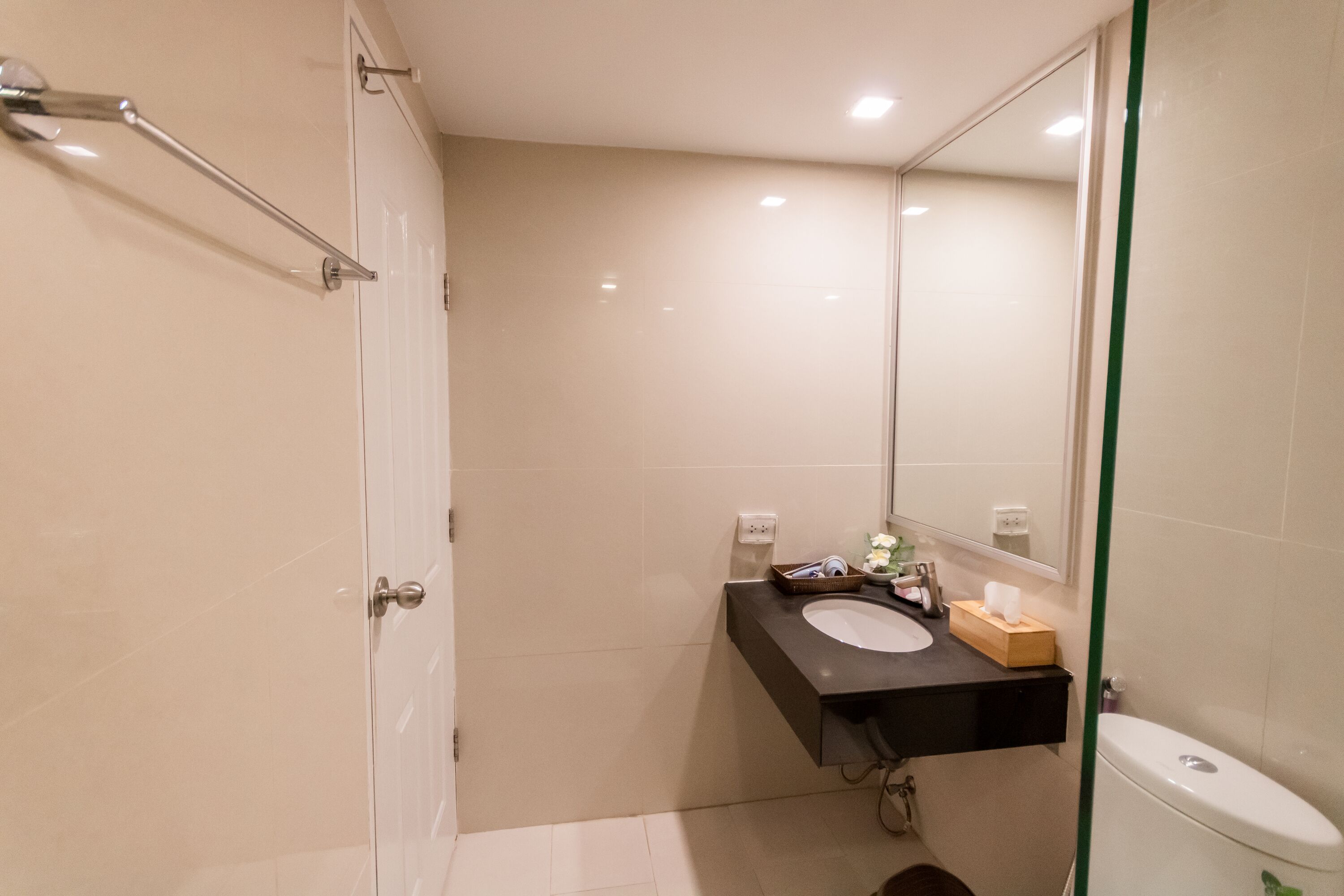 A modern bathroom with a white toilet, a black sink, and a mirror.