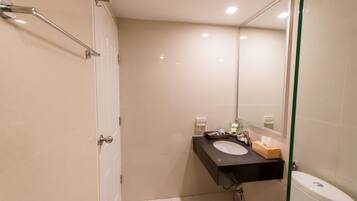 A modern bathroom with a white toilet, a black sink, and a mirror.