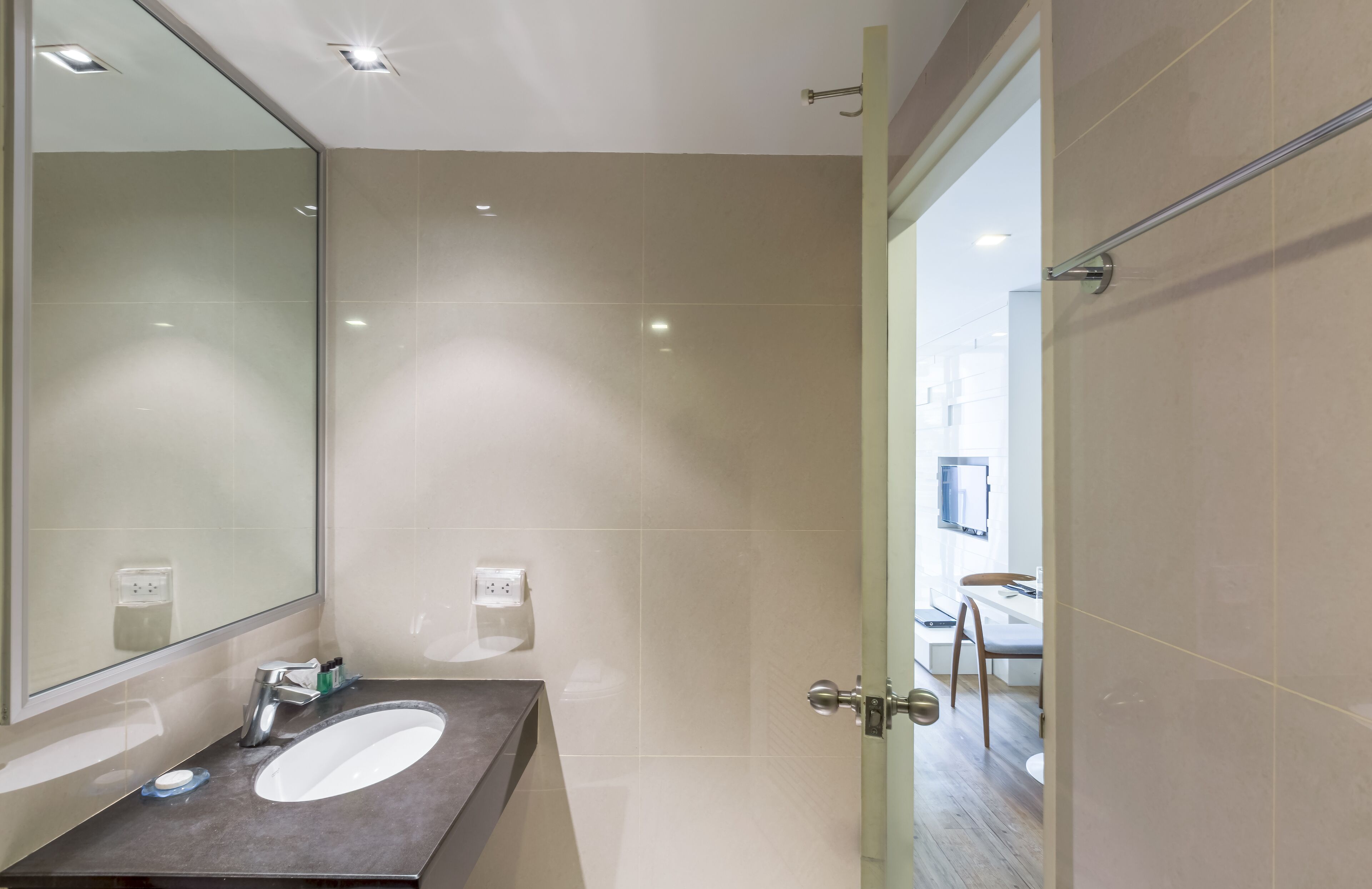 Un baño moderno con un espejo grande, un lavabo y una zona de ducha.