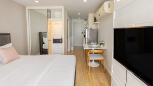 Quarto de hotel moderno com uma cama grande, uma escrivaninha e uma televisão.