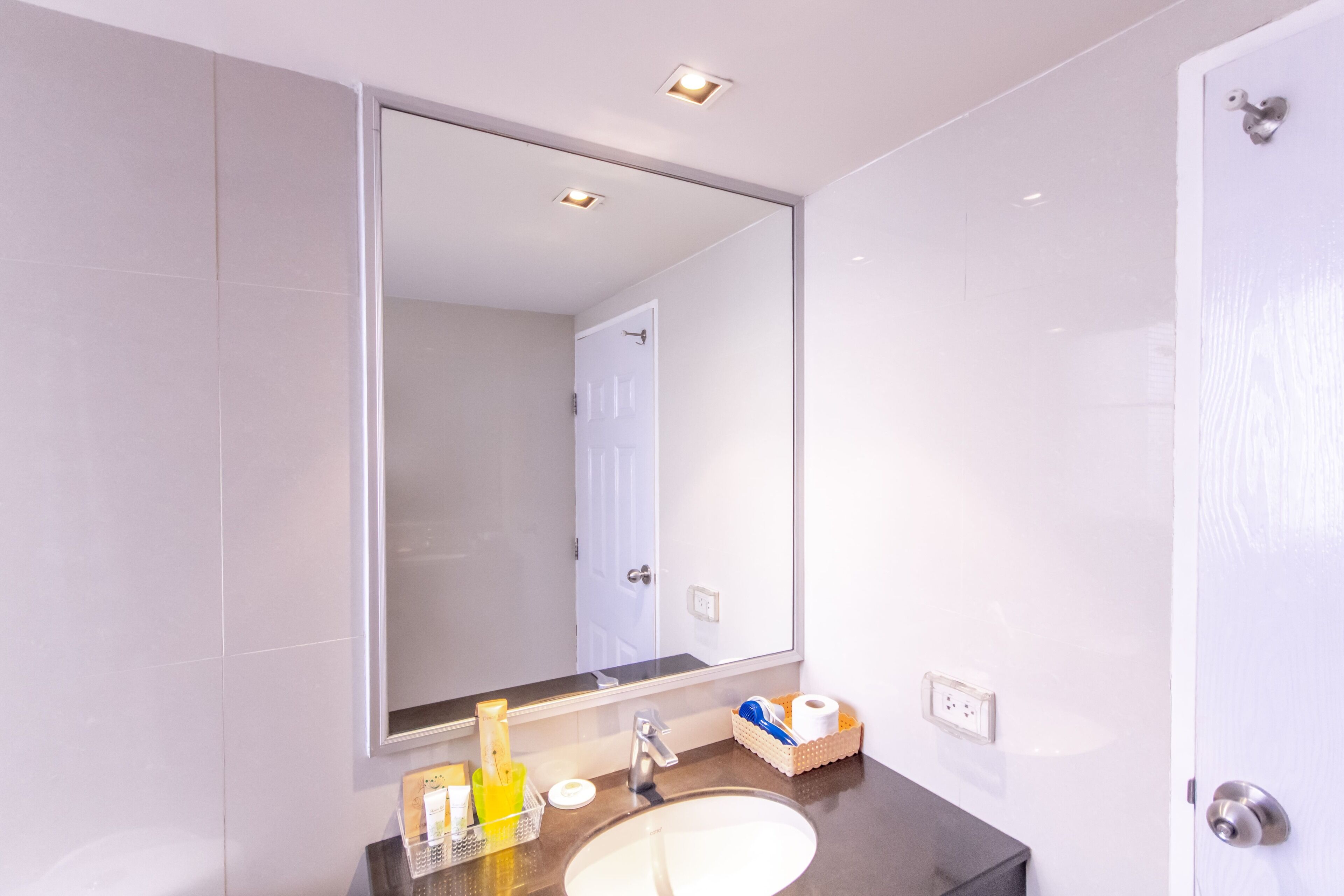 A modern bathroom with a large mirror, a sink, and a toilet.
