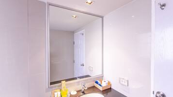 A modern bathroom with a large mirror, a sink, and a toilet.