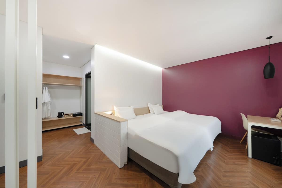 Ein modernes Hotelzimmer mit Bett, Nachttisch, Schreibtisch und Kleiderschrank.