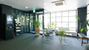 Eine moderne Lobby mit Selbstcheck-in-Terminal, Sitzgelegenheiten und großen Fenstern.
