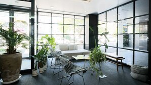 Ein modernes Interieur mit einer Couch, Stühlen und Zimmerpflanzen.