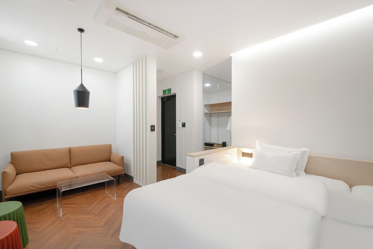 Una habitación de hotel con cama, sofá, una mesita y un espejo.