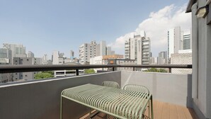 Ein Balkon mit einem Metalltisch und -stühlen, mit Blick auf eine Skyline moderner Gebäude.