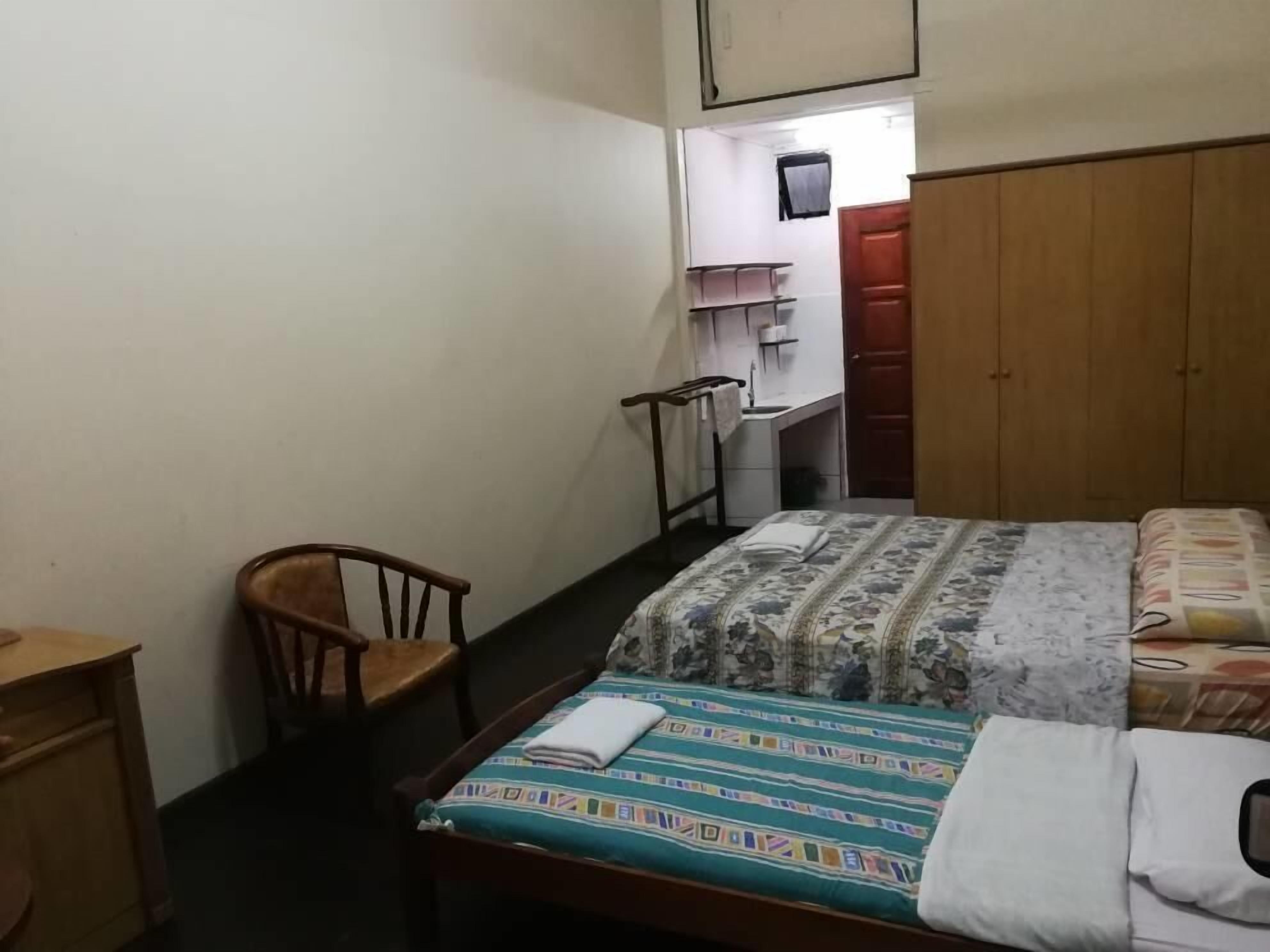 A bedroom with a bed, a wooden chair, a desk, and a wardrobe.
