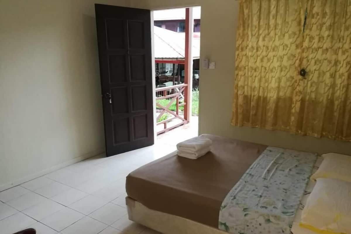 A bedroom with a bed, a door leading outside, and a window with curtains.