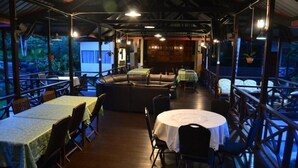An outdoor dining area with tables and chairs, a sofa, and a covered walkway. - Slagon Homestay (Ranau)