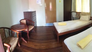 A hotel room with a wooden floor, a desk with a chair, two single beds, and a wardrobe. - Slagon Homestay (Ranau)