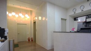 A hotel reception area with a counter, clocks, and a fire extinguisher. - Havana Hotel (Gwangju)