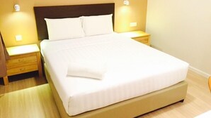 Una cama bien hecha con sábanas blancas en una habitación de hotel.