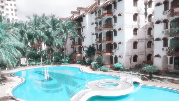 Una piscina grande y curvada rodeada por un edificio de varios pisos con balcones.