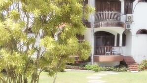Un edificio con fachada blanca, un balcón con barandilla de metal y una escalera que lleva a la entrada.