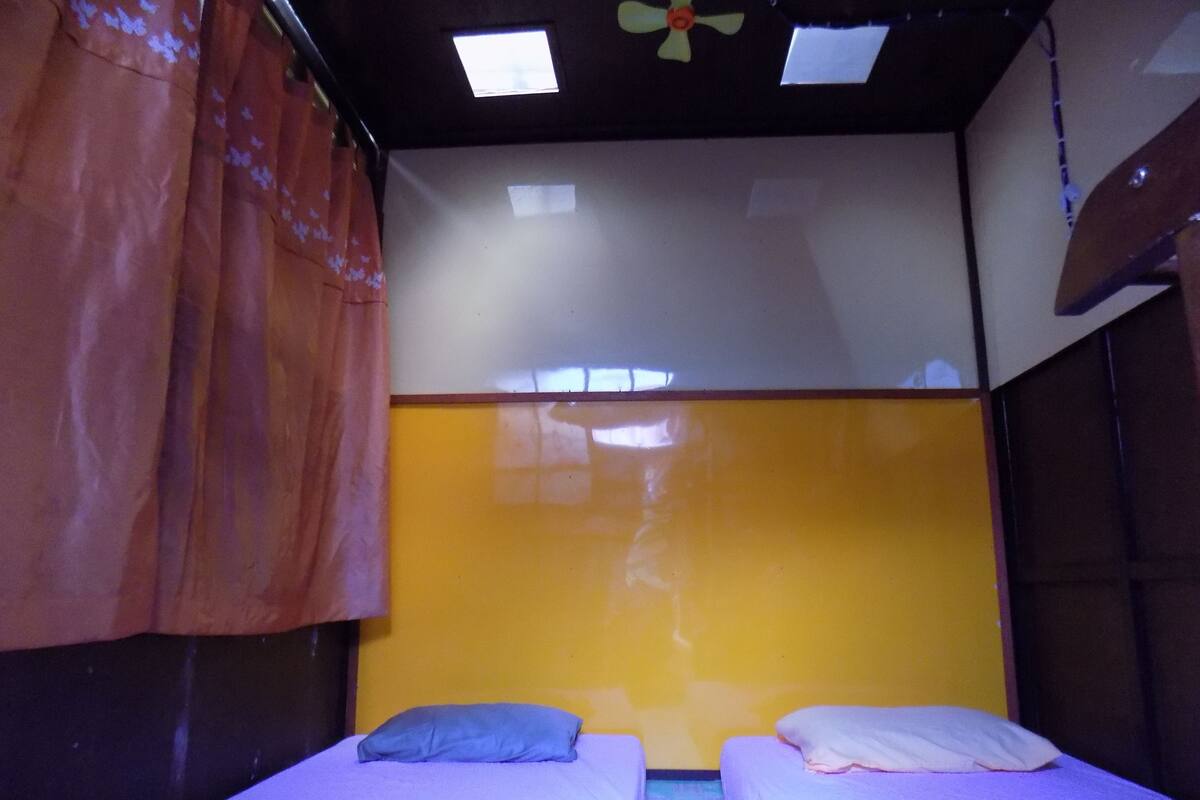 Una habitación con dos camas, un ventilador de techo y una ventana.