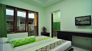 A bedroom with a bed, a TV mounted on the wall, and a window with curtains. - The Ayudya Glogor Carik (Denpasar)