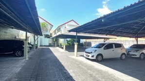 A parking area with covered carports and a paved walkway. - The Ayudya Glogor Carik (Denpasar)