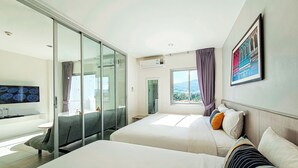 Una habitación de hotel moderna con dos camas, un ventanal con vistas, un televisor de pantalla plana y un baño con bañera.