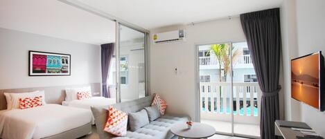 Habitación de hotel con dos camas, un sofá, una mesita, un televisor y un balcón con vistas al exterior.