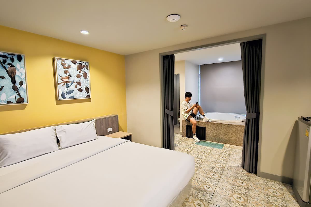 A hotel room with a bed, a desk, a bathroom with a bathtub, and a shower.