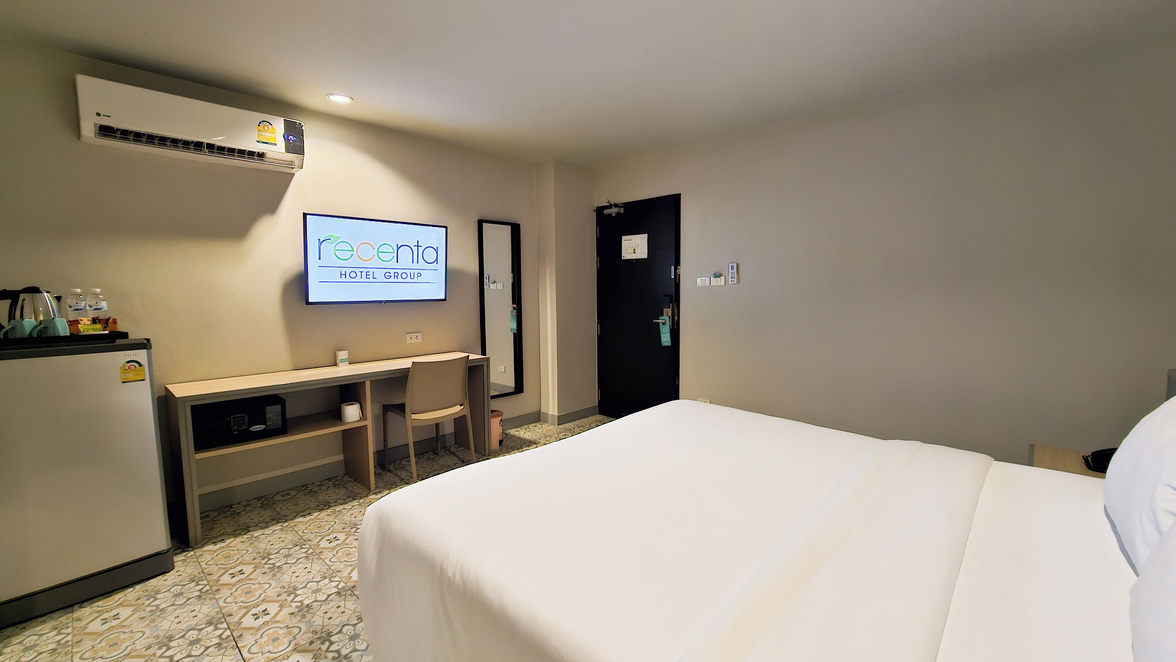 Camera d'albergo con un letto, una scrivania, una sedia, una televisione e un condizionatore d'aria.