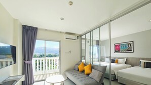 Una habitación de hotel moderna con balcón, sofá, cama y escritorio con televisor.