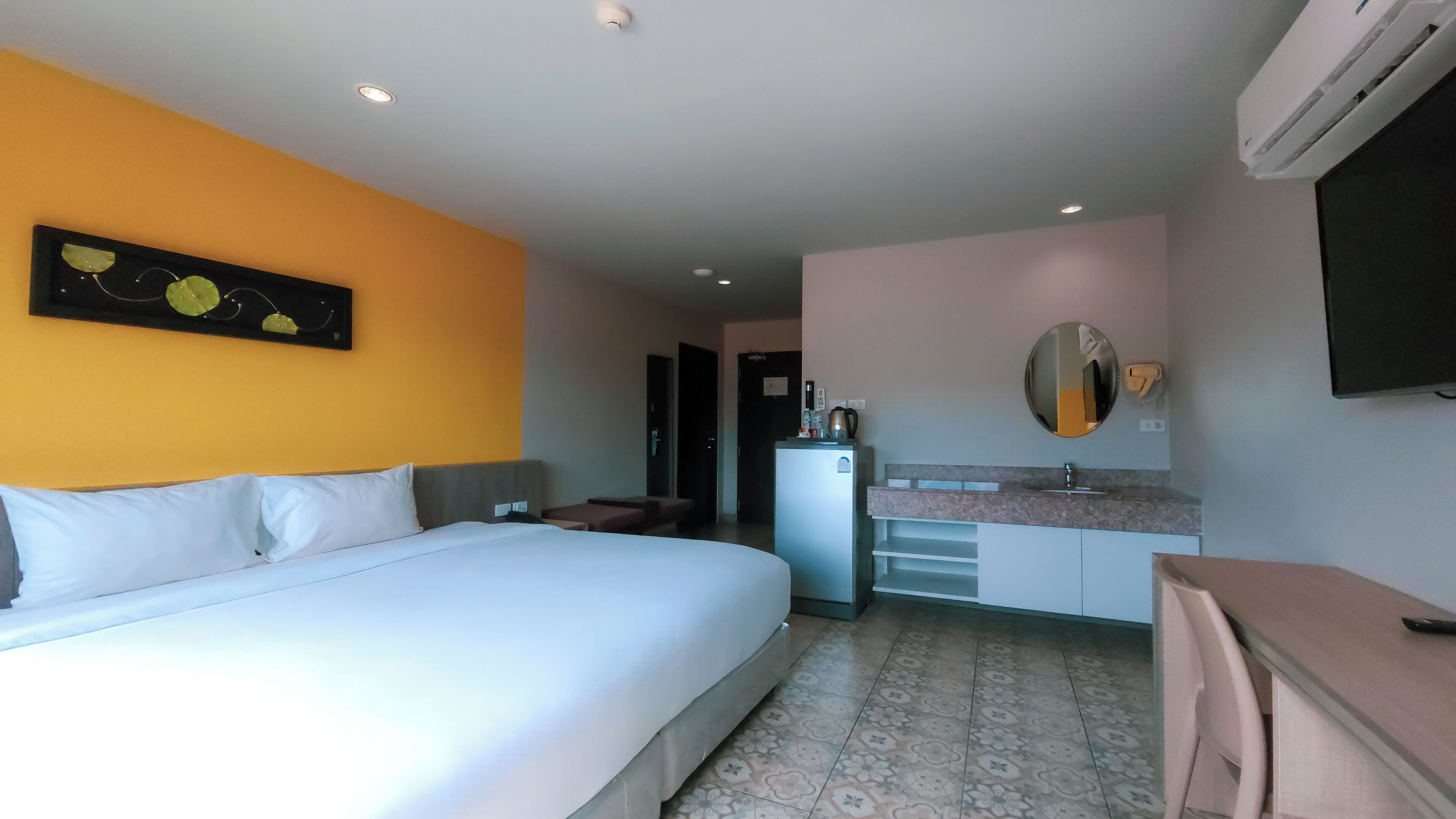 Een hotelkamer met een bed, een kitchenette, een spiegel en een televisie.