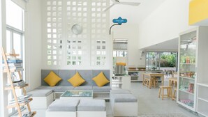 Un interior moderno con un sofá, otomanas, una mesa de centro, una estantería y una zona de cocina.