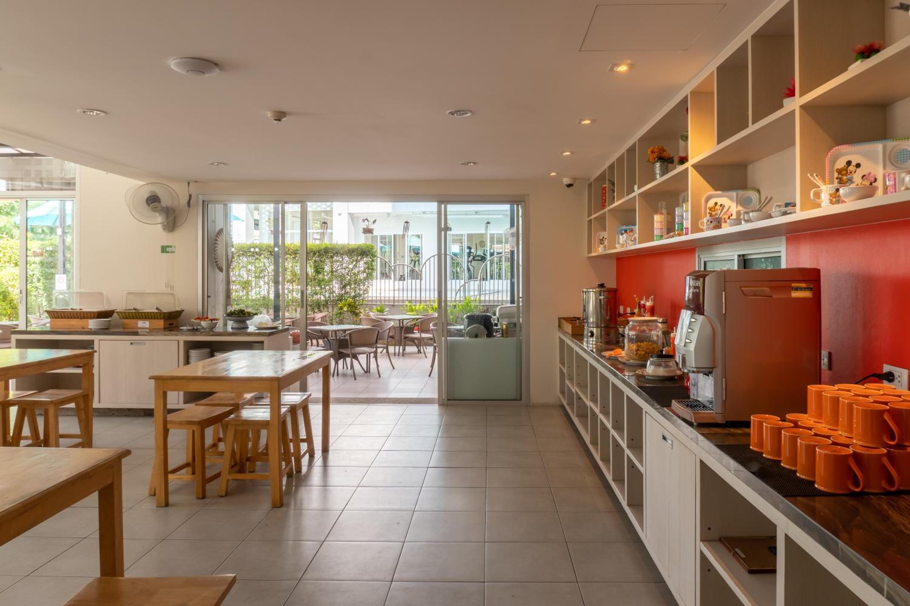 Une cuisine spacieuse avec des tables et des chaises en bois, un coin café et une vue sur l’espace extérieur.