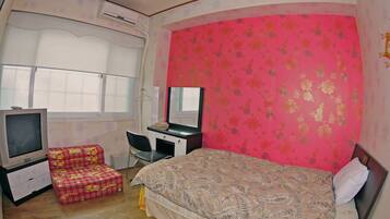A bedroom with a bed, a desk, a chair, and a television.