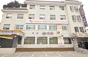 Ein mehrstöckiges Gebäude mit einem Schild für 'Hwaseong Guest House' und einem weiteren Schild für 'Sunlight'.