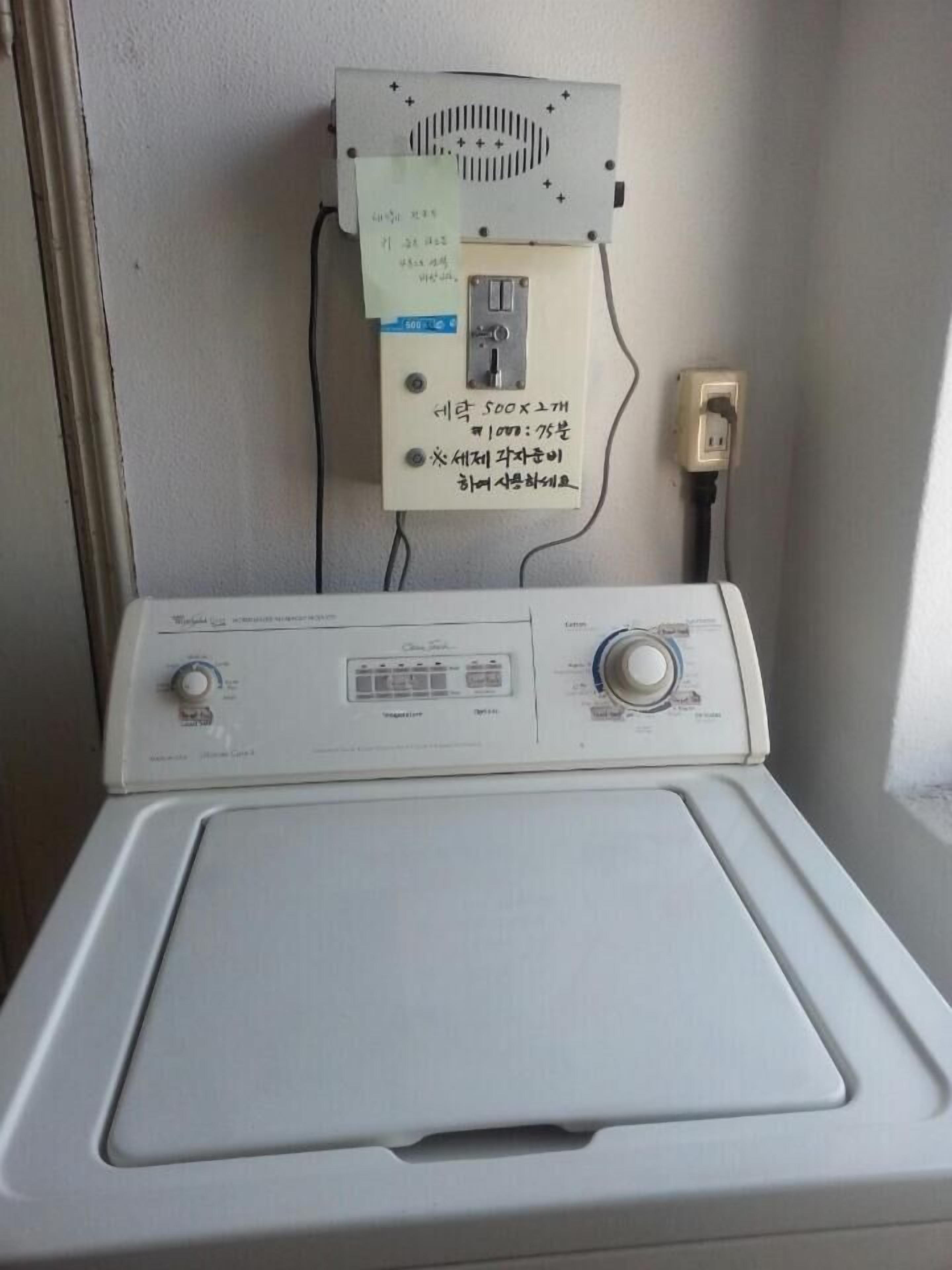 Una lavadora de carga frontal con un panel de control y un enchufe en la pared.