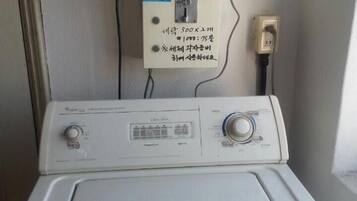 Una lavadora de carga frontal con un panel de control y un enchufe en la pared.