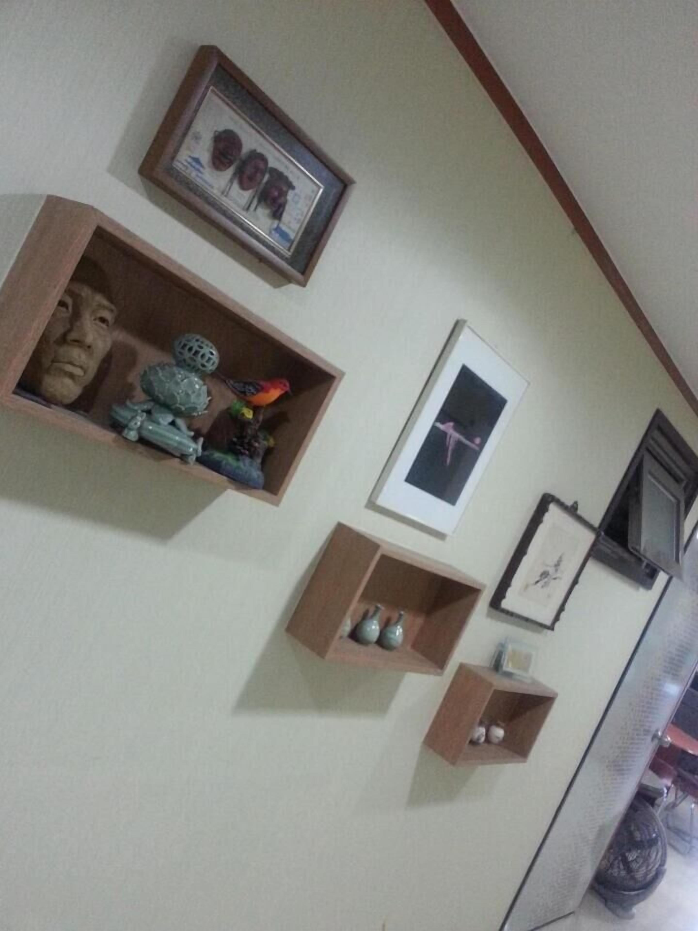 A room with multiple wooden shelves displaying various decorative items, a framed picture on the wall, and a window with a closed blind.